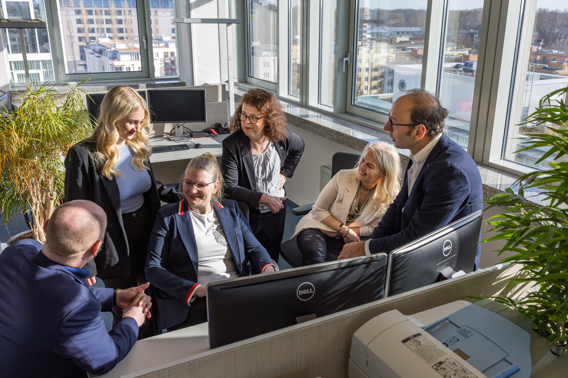 Das Team der Reisebürokooperation Deutscher Reisering im Austausch an einem Arbeitsplatz im Berliner Büro